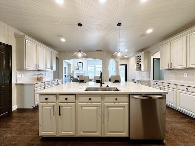 kitchen featuring a kitchen island with sink, pendant lighting, backsplash, dishwasher, and sink