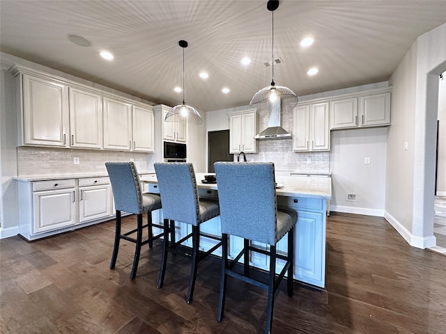 kitchen featuring hanging light fixtures, white cabinetry, dark hardwood / wood-style floors, a kitchen bar, and a center island with sink