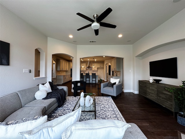 living room featuring dark wood-type flooring and ceiling fan