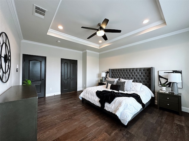 bedroom featuring a tray ceiling, dark hardwood / wood-style flooring, crown molding, and ceiling fan