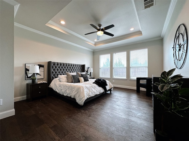 bedroom featuring a textured ceiling, a tray ceiling, dark wood-type flooring, ceiling fan, and ornamental molding