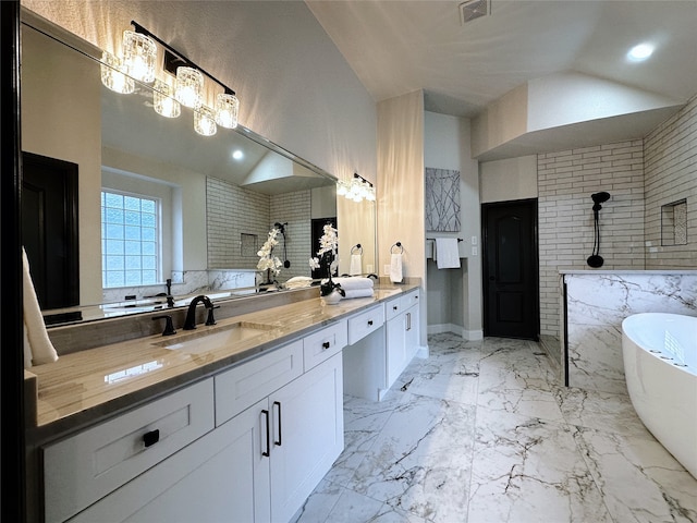 bathroom with a tub to relax in, vanity, lofted ceiling, and brick wall