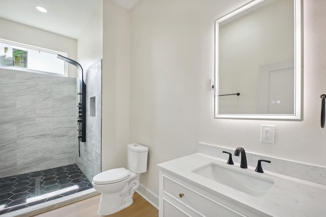 bathroom with vanity, hardwood / wood-style floors, toilet, and tiled shower