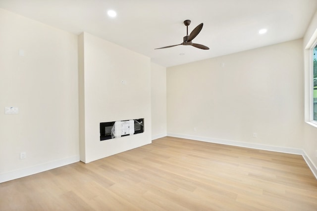 unfurnished living room featuring light hardwood / wood-style flooring, ceiling fan, and a fireplace