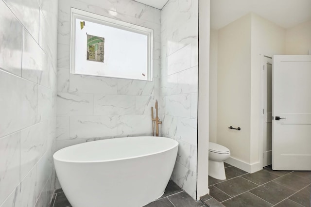 bathroom with a tub to relax in, tile walls, and toilet