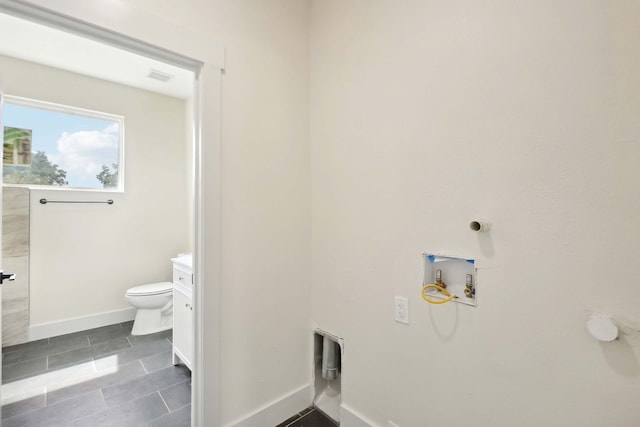 washroom featuring washer hookup and dark tile patterned flooring