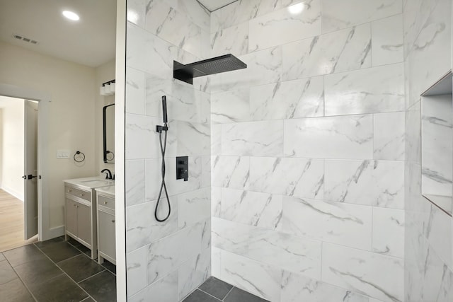 bathroom with a tile shower and vanity