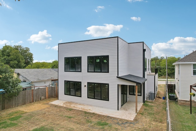 rear view of house featuring a lawn, a patio, and central AC