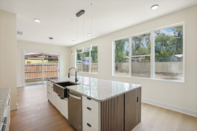 kitchen featuring sink, an island with sink, white cabinets, hanging light fixtures, and light hardwood / wood-style flooring