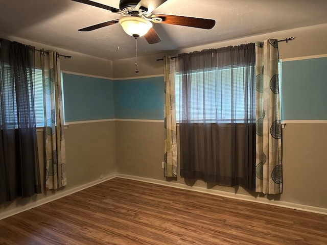 empty room with baseboards, wood finished floors, and a ceiling fan