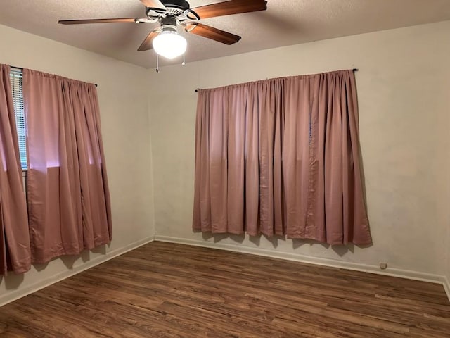 spare room with baseboards, dark wood-type flooring, and a textured ceiling