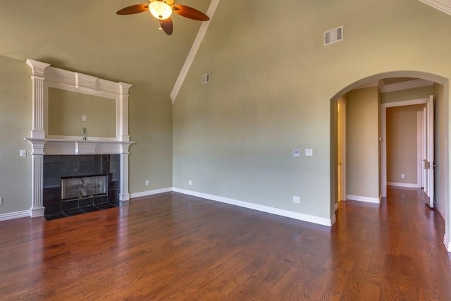 unfurnished living room featuring a tiled fireplace, crown molding, dark hardwood / wood-style flooring, and ceiling fan