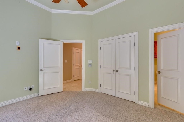 unfurnished bedroom featuring ornamental molding, ceiling fan, light colored carpet, and a closet