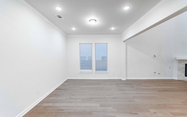 empty room featuring ornamental molding, a fireplace, and light hardwood / wood-style flooring