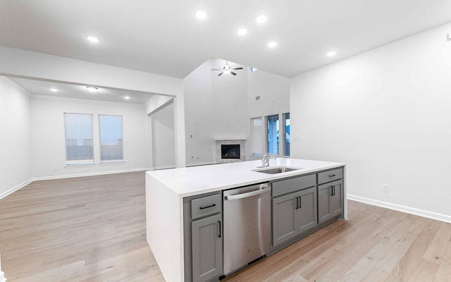 kitchen with ceiling fan, a kitchen island with sink, sink, dishwasher, and gray cabinets