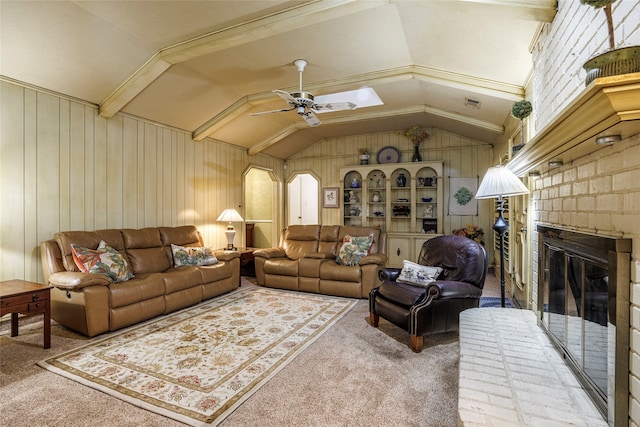 carpeted living room with lofted ceiling, ceiling fan, wood walls, and a fireplace