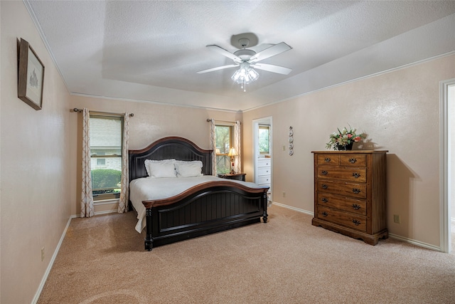 carpeted bedroom featuring a textured ceiling, ceiling fan, a tray ceiling, and multiple windows