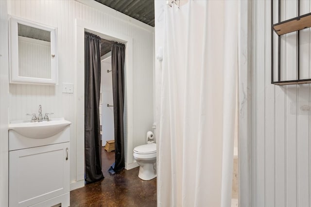 bathroom with vanity, toilet, wooden walls, and concrete flooring