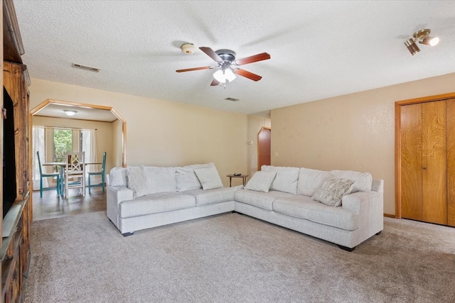 carpeted living room featuring a textured ceiling and ceiling fan