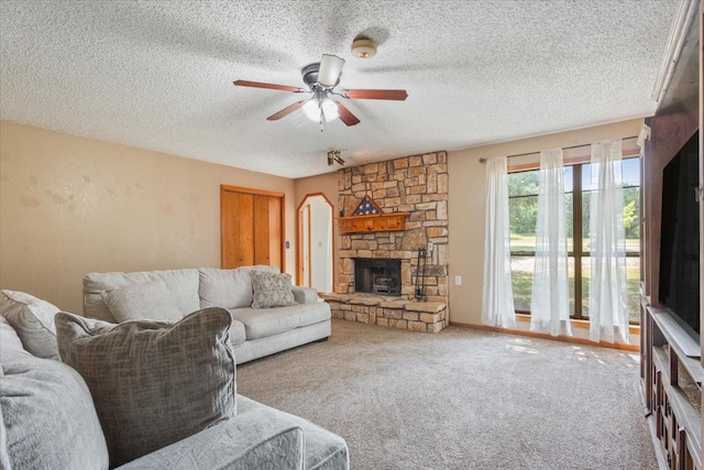 living room with a fireplace, a textured ceiling, ceiling fan, and carpet