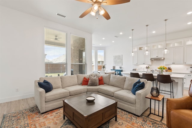 living room with light hardwood / wood-style flooring and ceiling fan