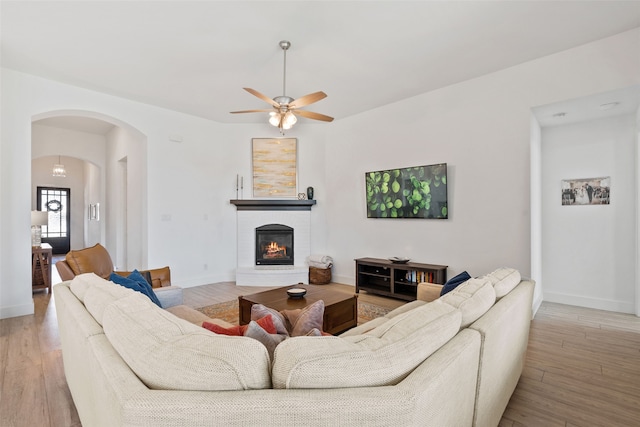 living room with light hardwood / wood-style flooring, a brick fireplace, and ceiling fan