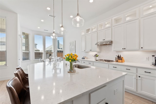 kitchen featuring white cabinets, a wealth of natural light, and an island with sink