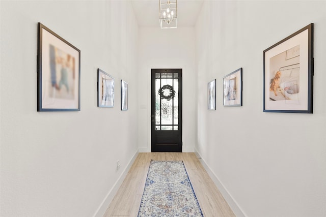 doorway to outside with light hardwood / wood-style flooring and a notable chandelier