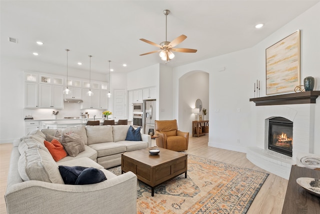 living room featuring ceiling fan, a fireplace, and light hardwood / wood-style floors