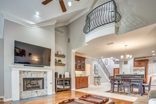 living room featuring ceiling fan with notable chandelier, light hardwood / wood-style floors, and ornamental molding