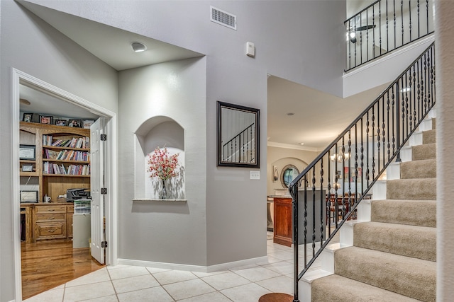 entryway with crown molding, a high ceiling, and light hardwood / wood-style flooring