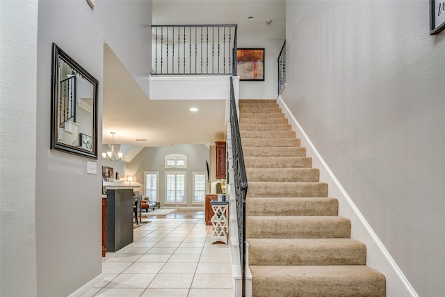 stairway with tile patterned floors and an inviting chandelier