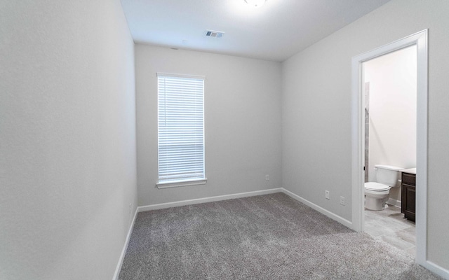 unfurnished bedroom featuring ensuite bath and light colored carpet