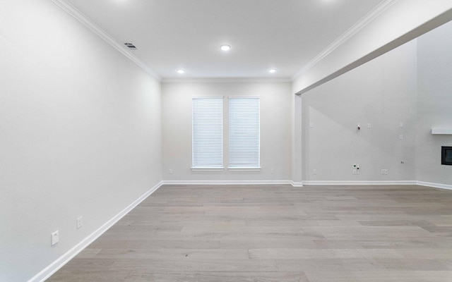 spare room featuring light wood-type flooring and crown molding