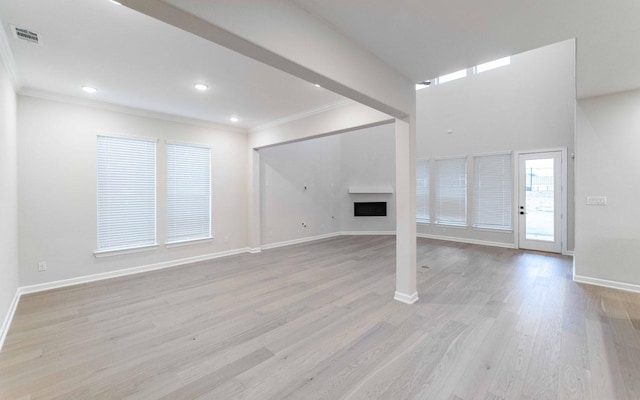 unfurnished living room featuring ornamental molding and light hardwood / wood-style flooring