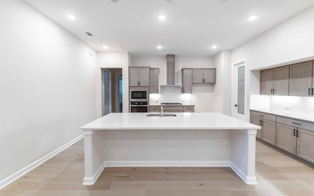 kitchen with stainless steel appliances, a large island, sink, and wall chimney exhaust hood