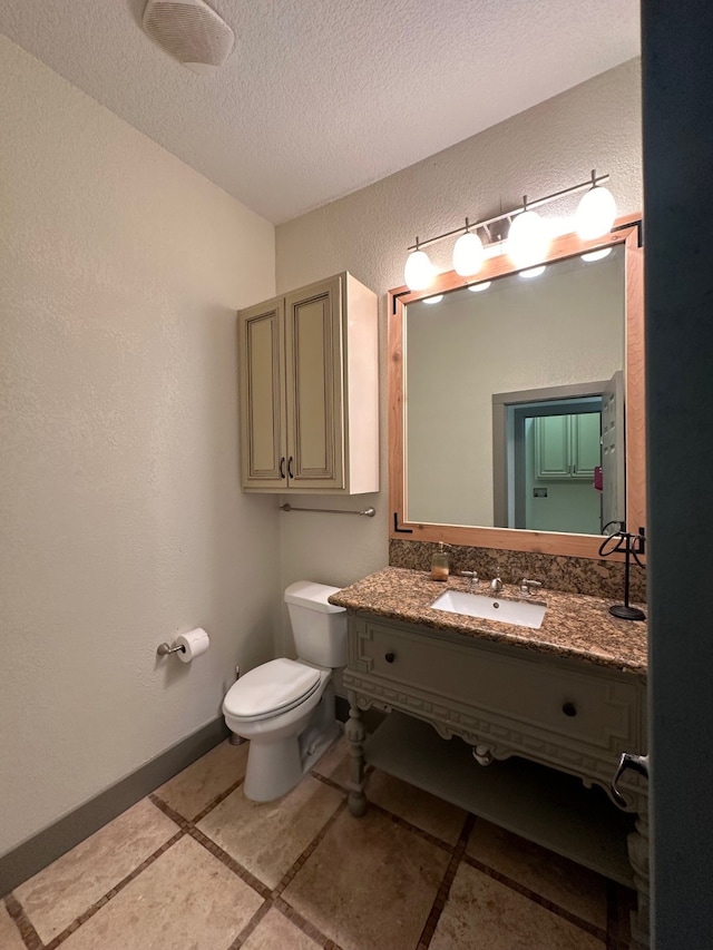 bathroom with a textured ceiling, tile patterned flooring, vanity, and toilet