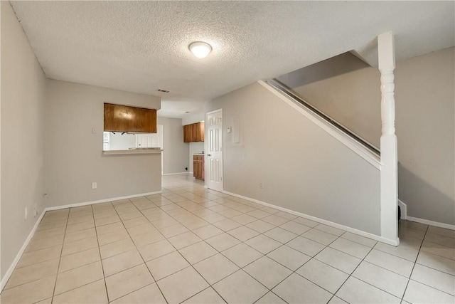 unfurnished room featuring a textured ceiling and light tile patterned flooring