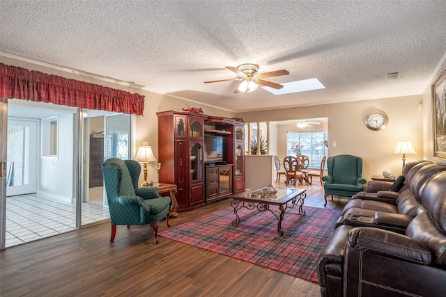 living room featuring a textured ceiling, ceiling fan, dark hardwood / wood-style flooring, and a skylight