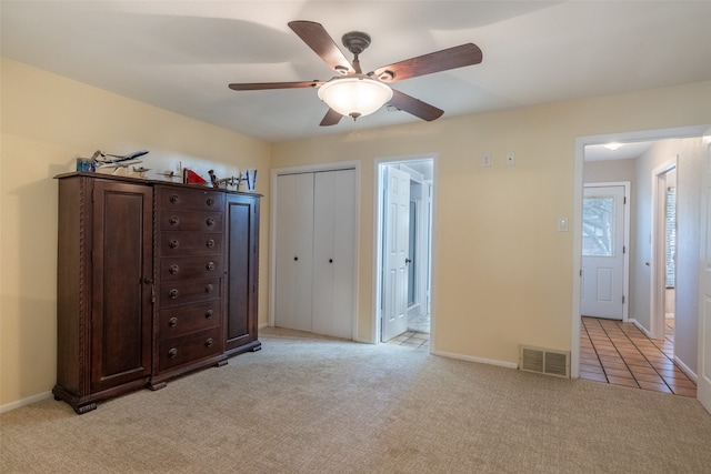 unfurnished bedroom with light colored carpet, ceiling fan, a closet, and ensuite bathroom