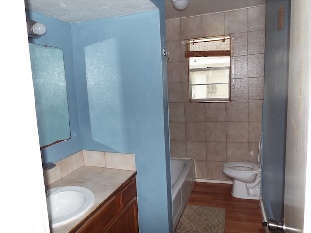 bathroom featuring hardwood / wood-style floors, toilet, a tub, tile walls, and vanity