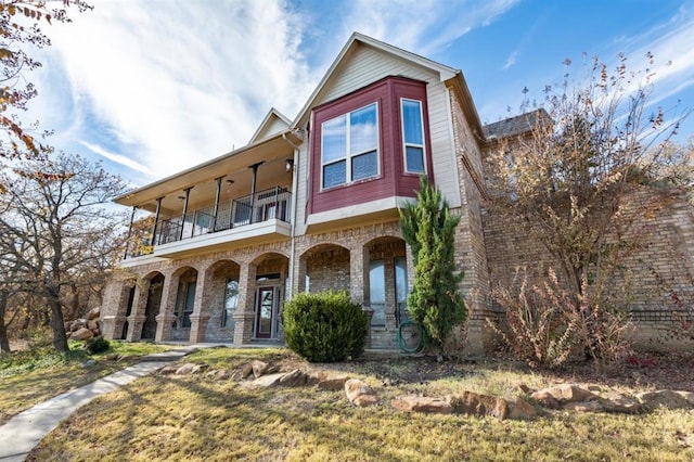 view of front of property with a balcony, a front lawn, and covered porch