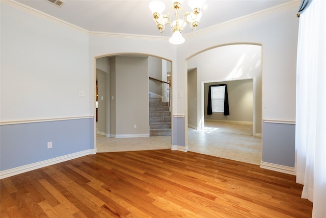 empty room featuring crown molding, a chandelier, and light wood-type flooring