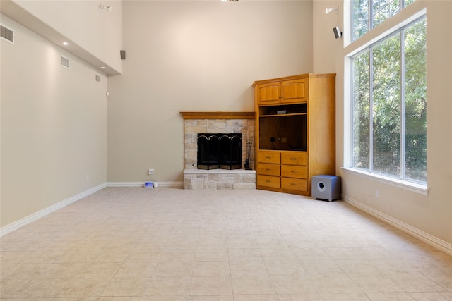 unfurnished living room with a stone fireplace and a towering ceiling