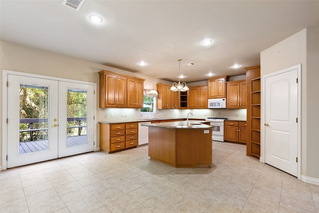 kitchen with white appliances, hanging light fixtures, a center island with sink, a notable chandelier, and french doors