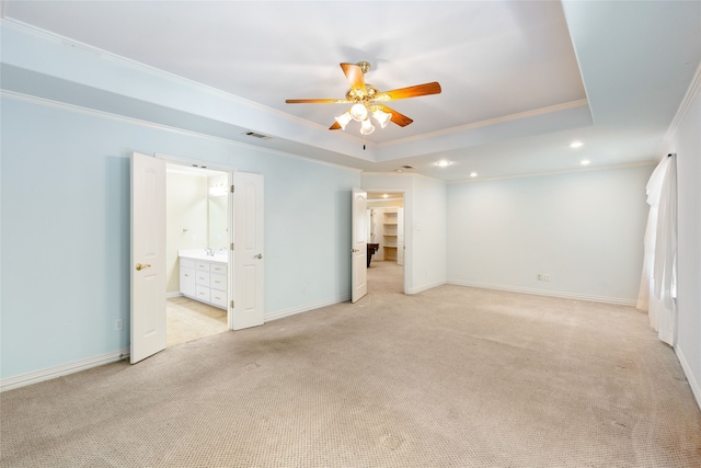 empty room with ceiling fan, light colored carpet, a raised ceiling, and ornamental molding