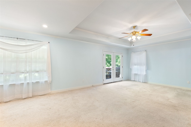 carpeted empty room featuring french doors, ornamental molding, a tray ceiling, and ceiling fan