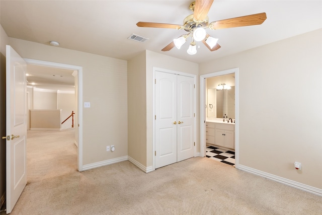 unfurnished bedroom with ceiling fan, connected bathroom, sink, a closet, and light carpet