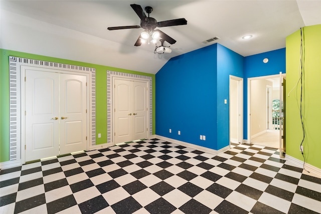 unfurnished bedroom featuring lofted ceiling, ceiling fan, and two closets