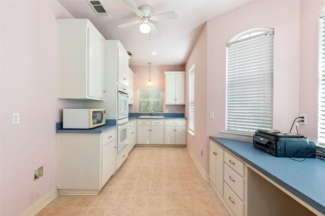 kitchen featuring ceiling fan, white cabinets, white appliances, sink, and hanging light fixtures